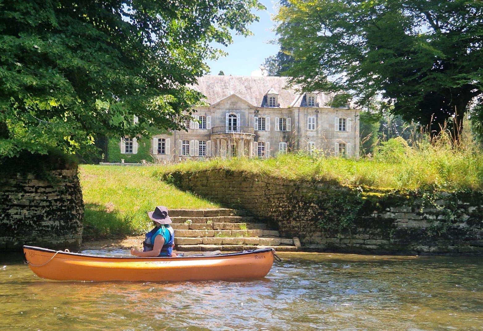 Ein ganz anderer Blick vom Wasser aus: Ein Paddler genießt in seinem orangen Boot beim Vorbei-Paddlen interessiert in die Garten eines kleinen Schlösschen