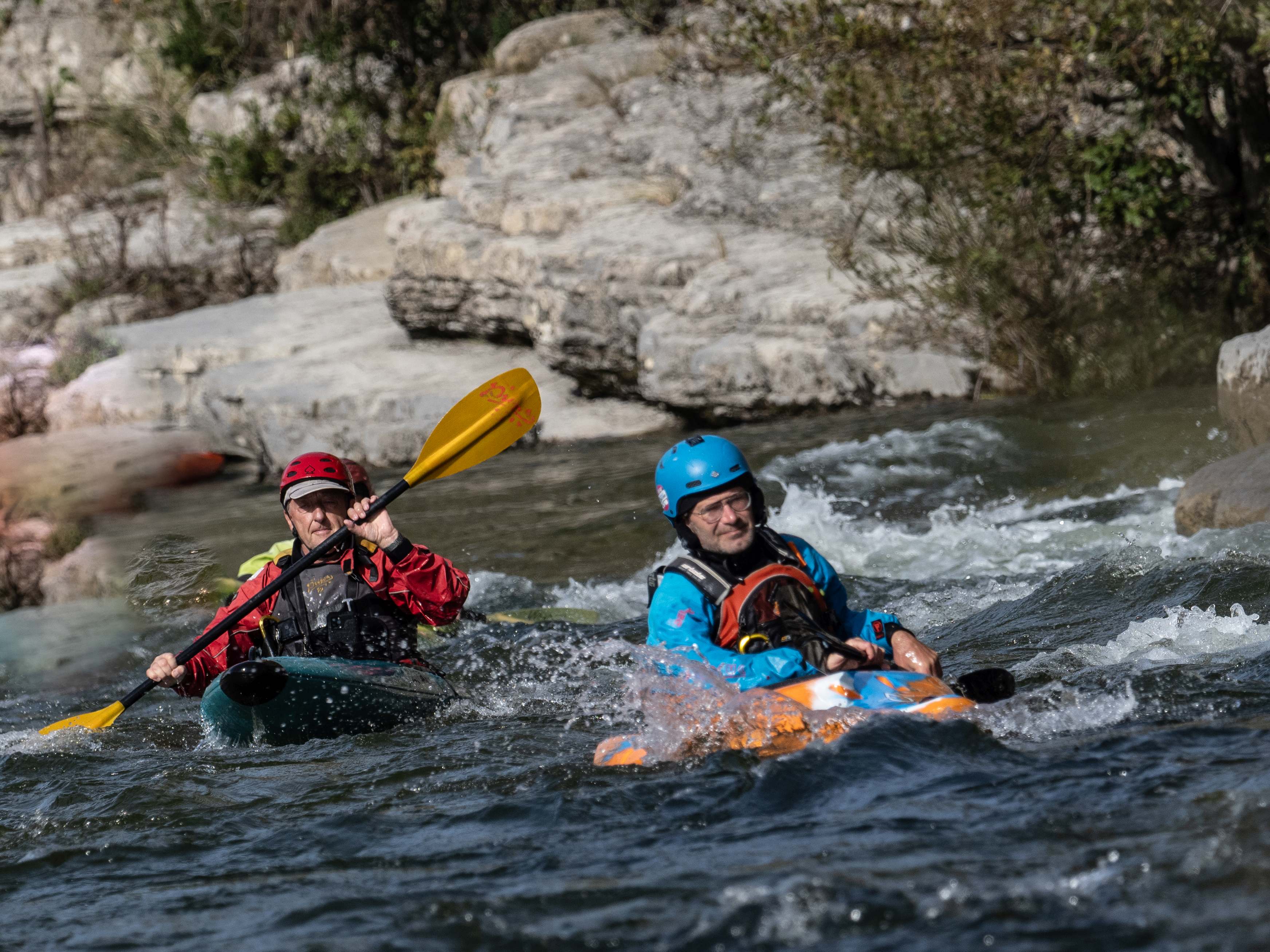 Zwei Paddler steuern hintereinander sicher um einen kleinen Felsvorsprung