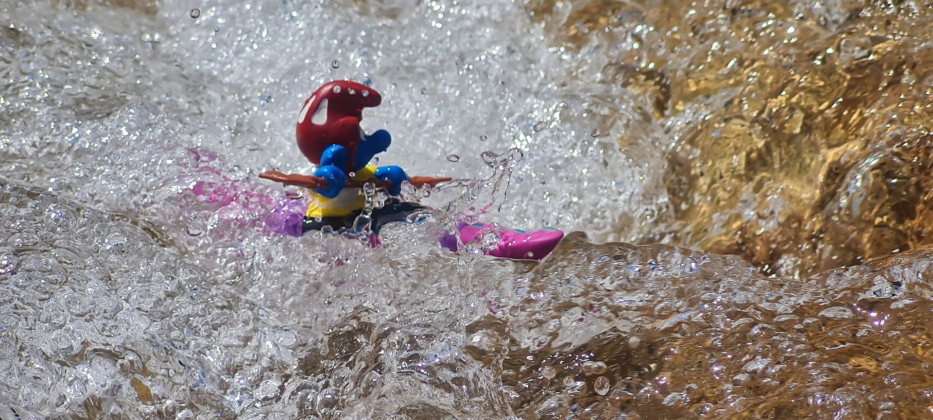 Der Schlumpf trainiert fleißig in seinem rosa Wildwasser-Kajak das Halten in einen Schwall