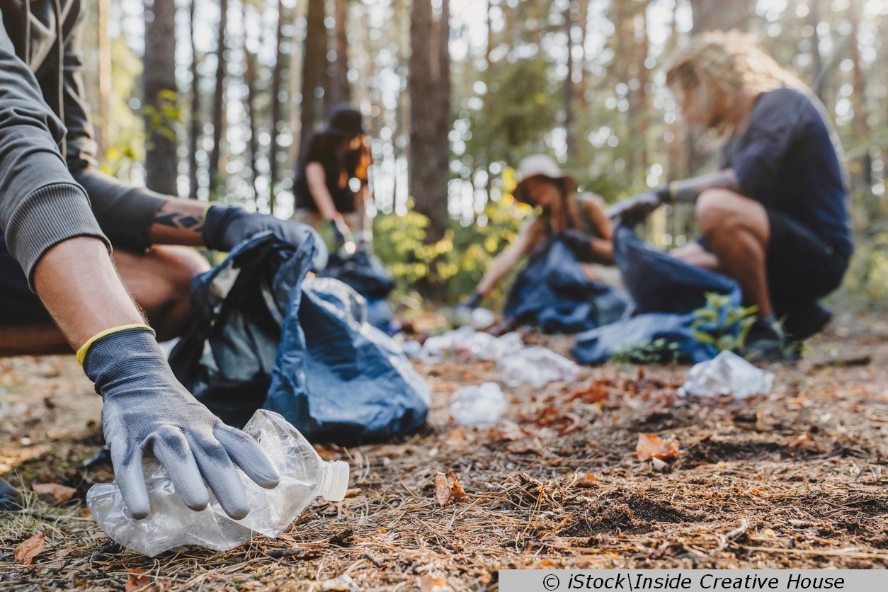 Einsatz für die Umwelt: Freiwillige sammeln in einem Wald Plastikflaschen und anderen Müll in Müllsäcken